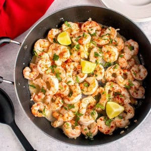 overhead view of shrimp in pan with lime, herbs