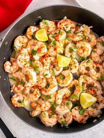 overhead view of shrimp in pan with lime, herbs