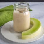 mason jar with smoothie and slice of honeydew, green napkin