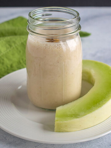 mason jar with smoothie and slice of honeydew, green napkin
