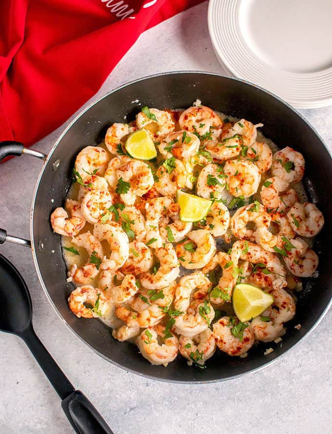 overhead view of shrimp in pan with lime, herbs