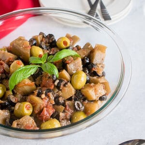 closeup view of bowl of eggplants with olives, basil