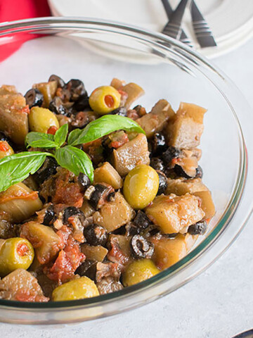 closeup view of bowl of eggplants with olives, basil