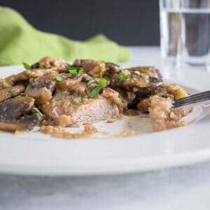 plate of meat with mushrroms, glass, napkin