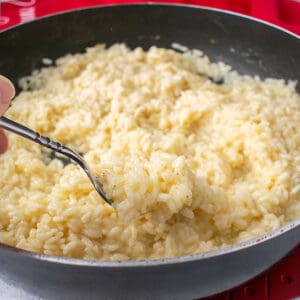 forkful of rice in a pan of risotto