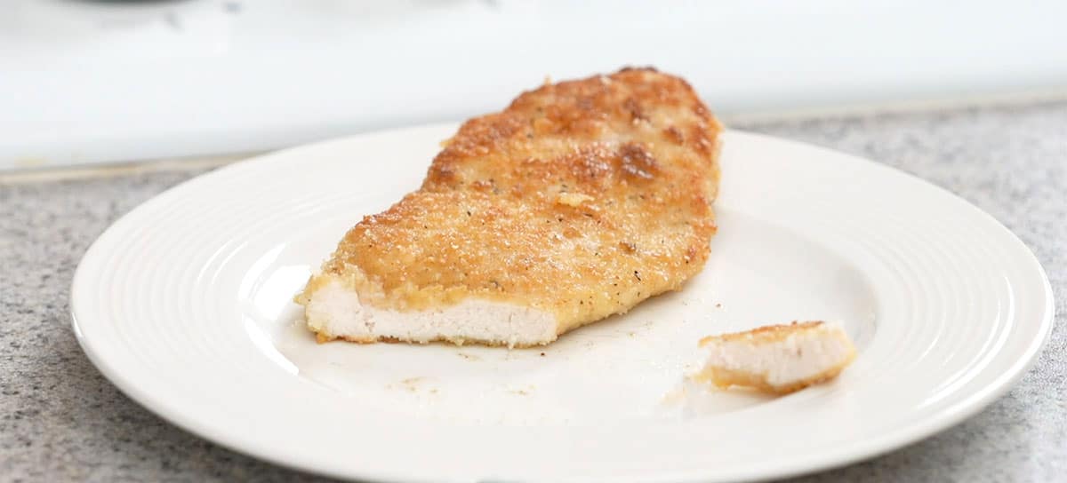 final breaded chicken cutlet cut open on plate