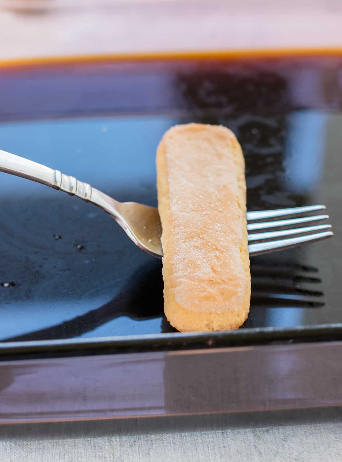 cookie resting on a fork held over dark liquid