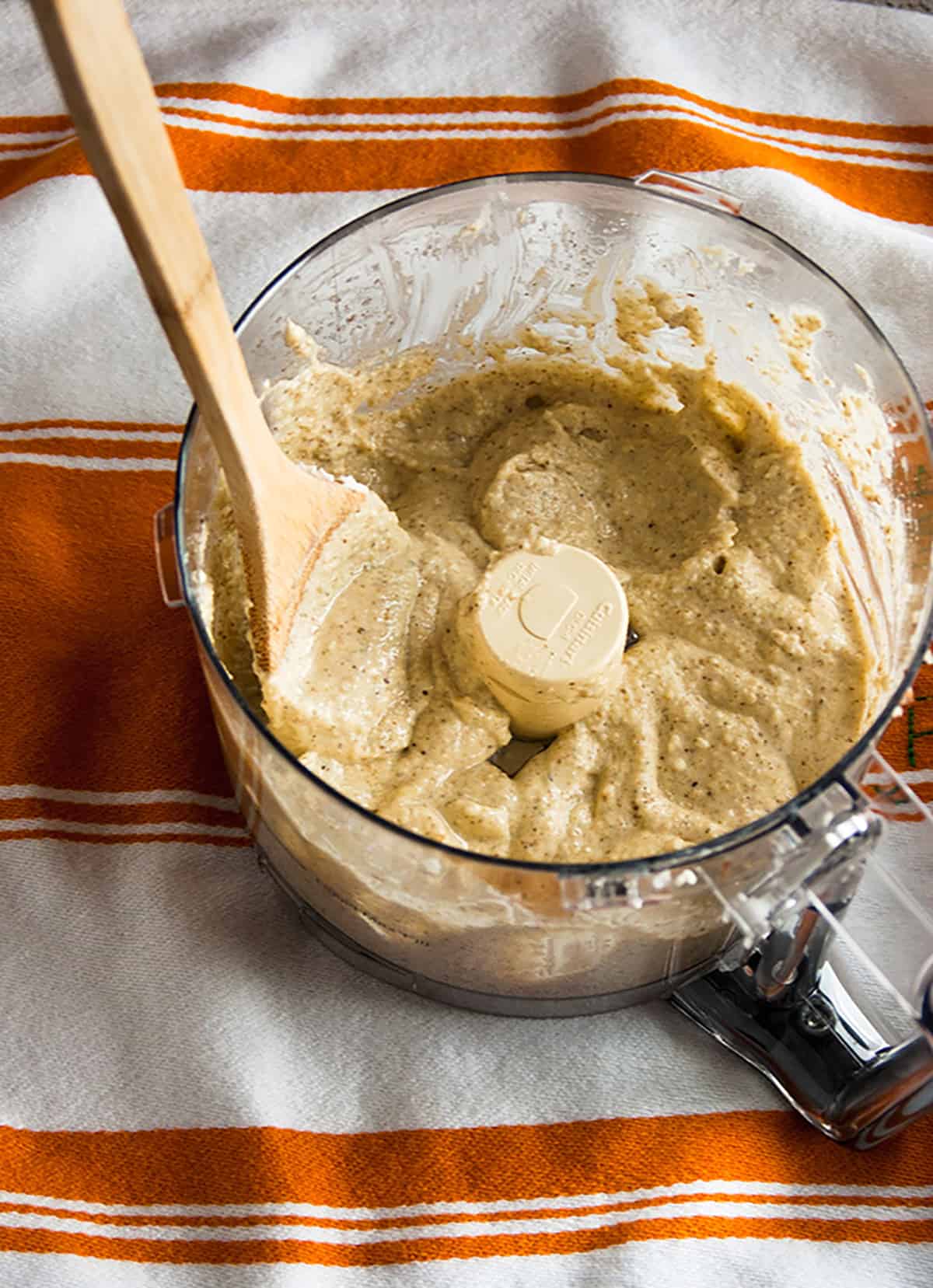 beige paste in food processor bowl with wooden spoon