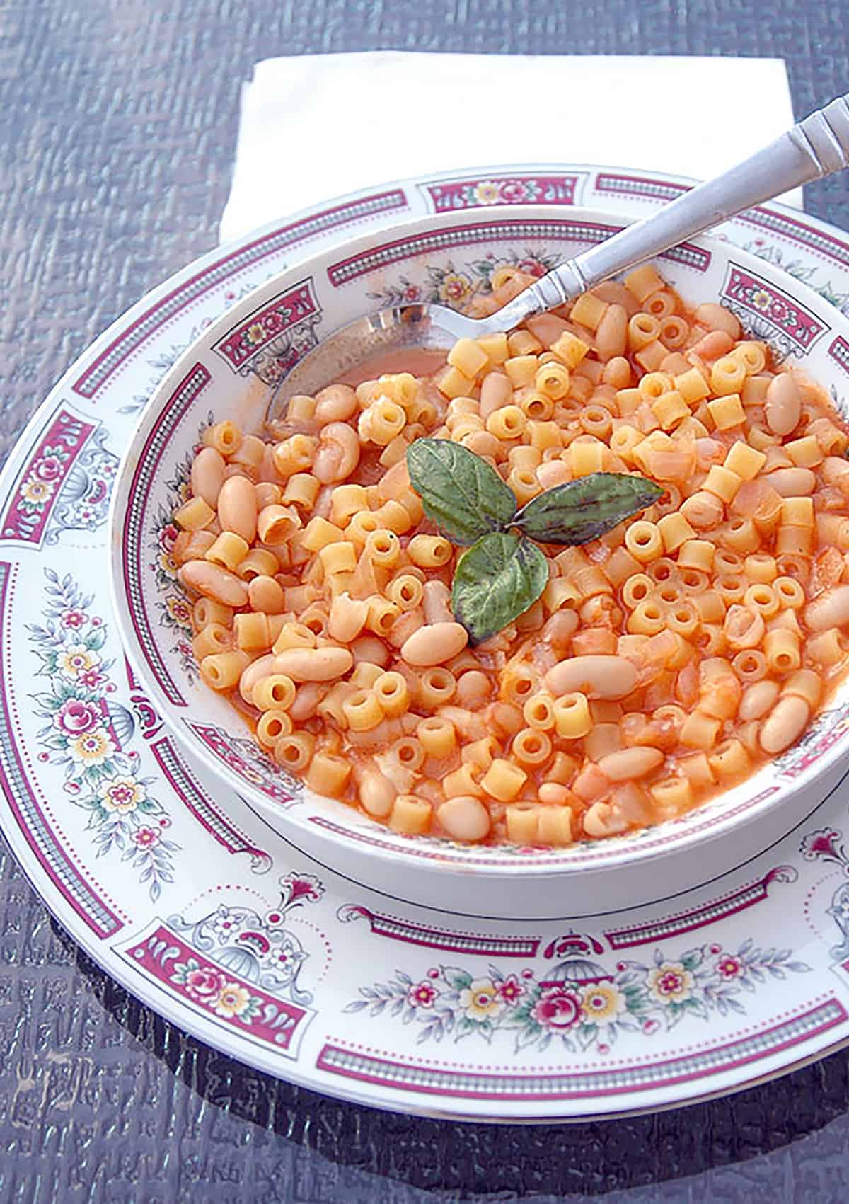 bowl of small pasta with beans and basil leaves