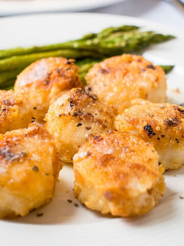 closeup of breaded broiled scallops with asparagus