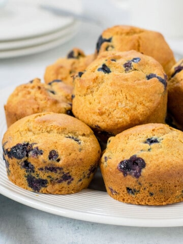 blueberry muffins stacked on a white plate