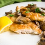cut open piece of chicken marsala with mushrooms and lemon