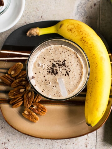 overhead view of smoothie with coffee grounds, banana, pecans
