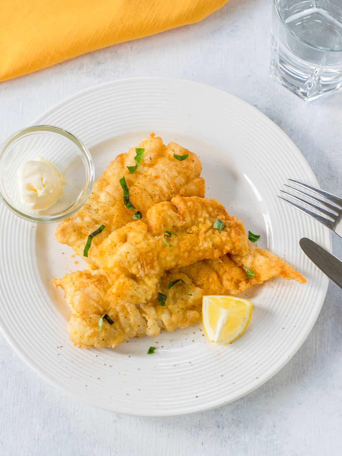 plate of fried cod with lemon wedge, mayo