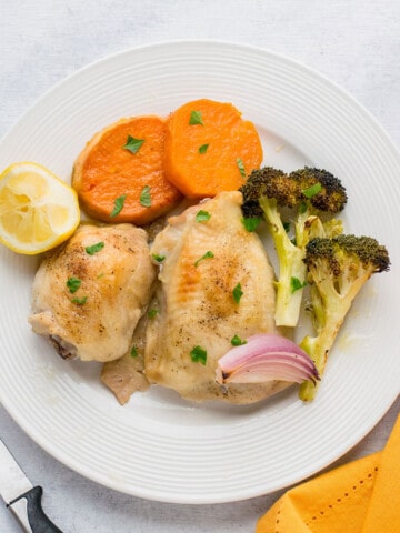 plate of roasted chicken thighs and vegetables with sweet potatoes