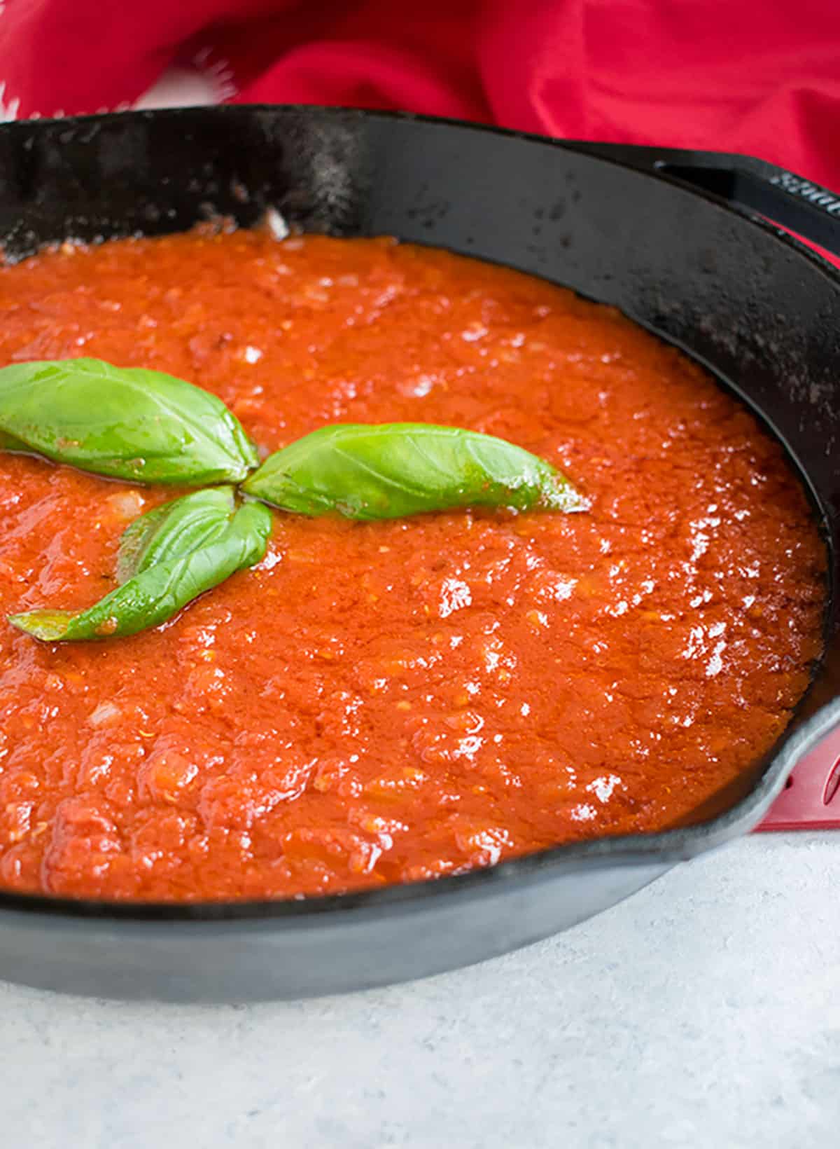 closeup of spaghetti sauce in black pan with basil 