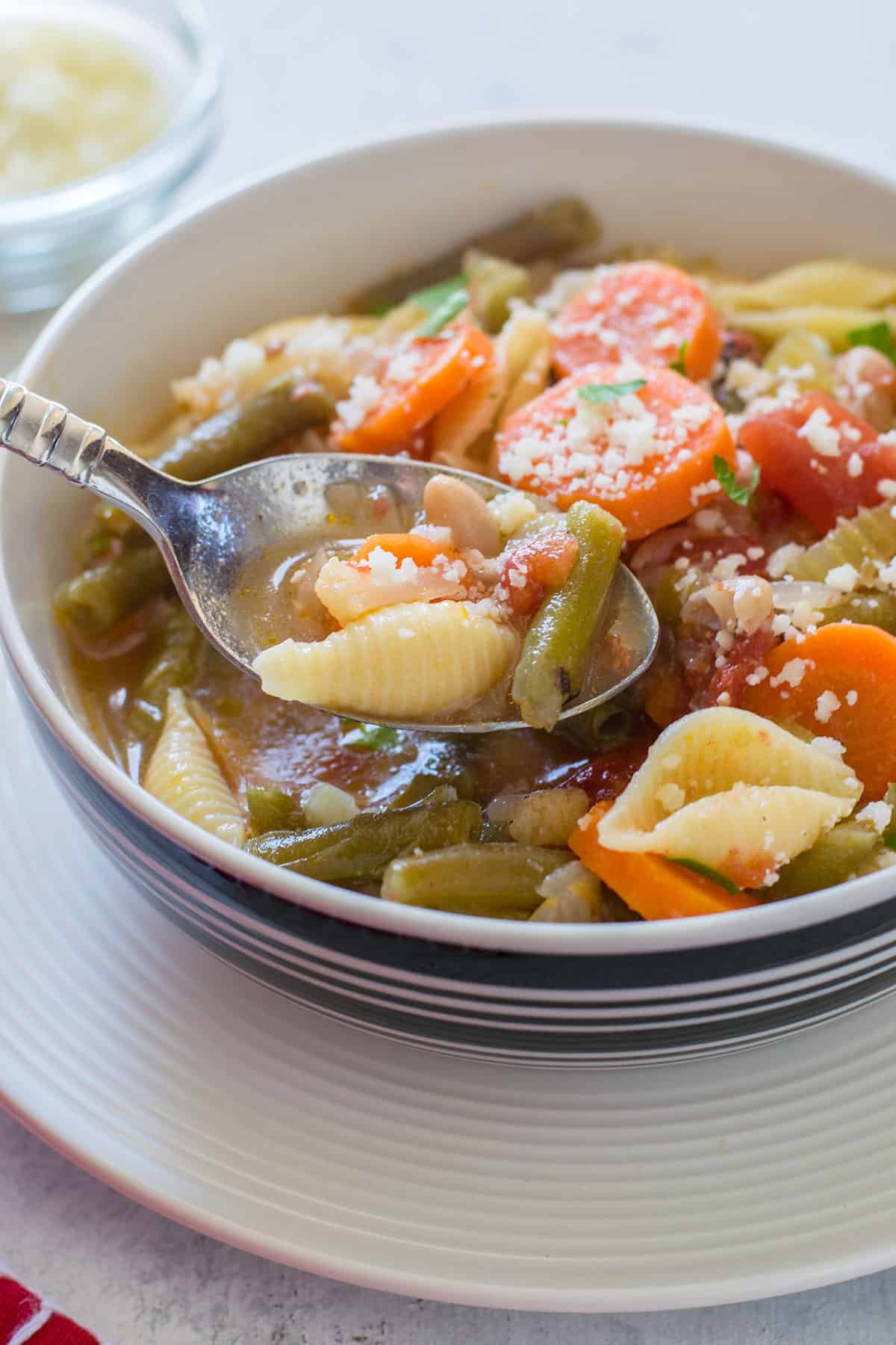 spoonful of soup with vegetables, pasta shells and white beans
