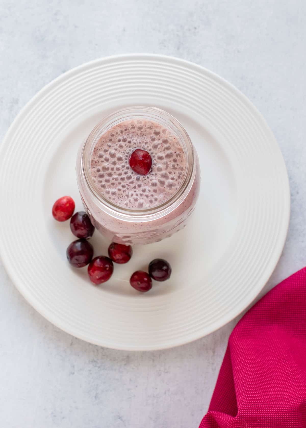 overhead view of cranberry smoothie in mason jar on plate