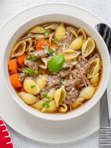 overhead view of bowl of beef soup with pasta shells