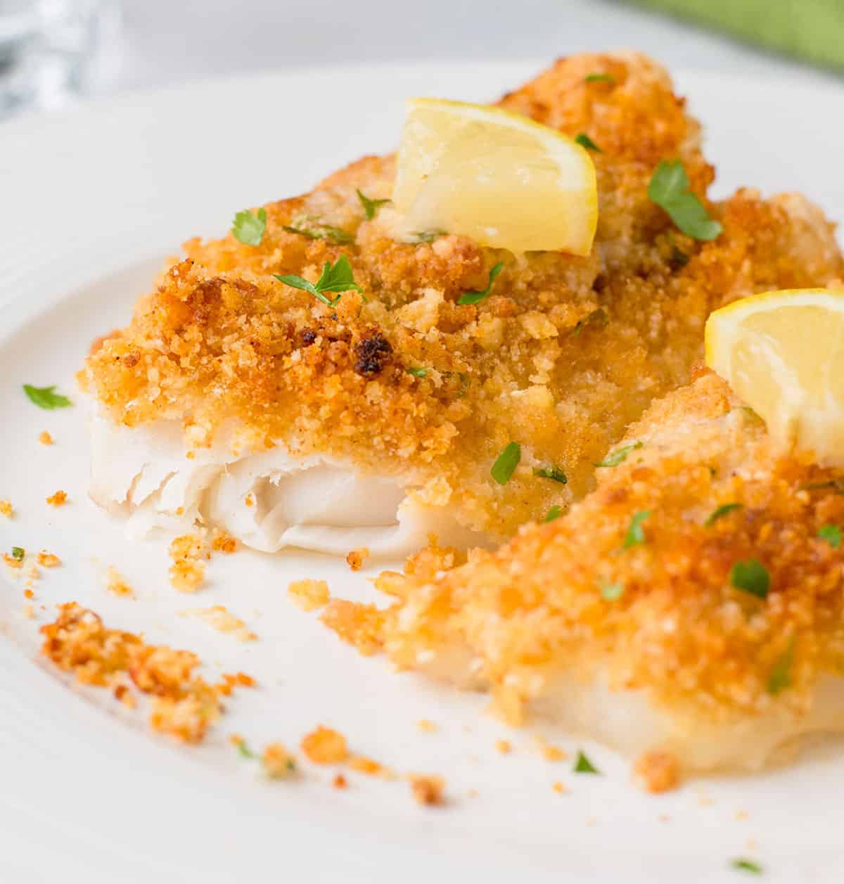 cod with bread crumb topping on plate with lemon wedges