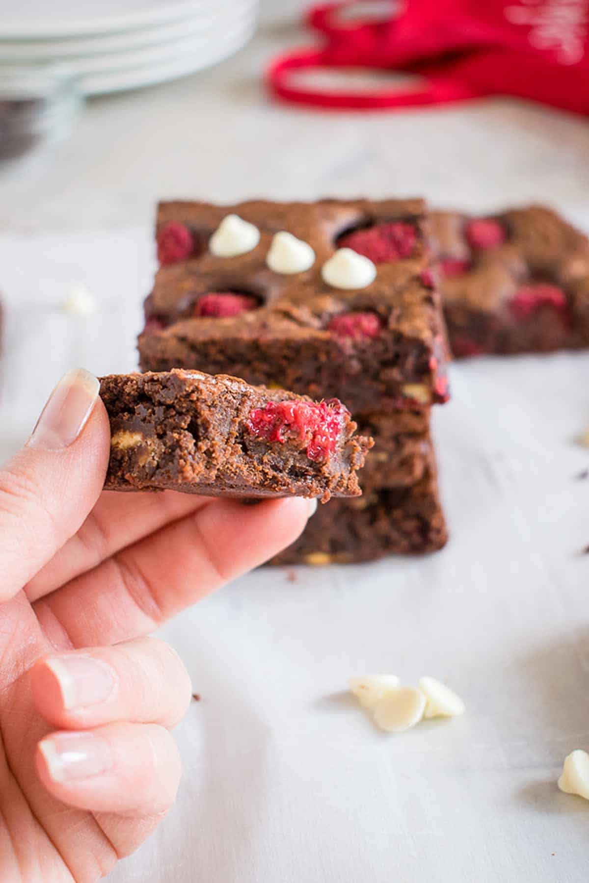 holding raspberry brownie with bite missing.