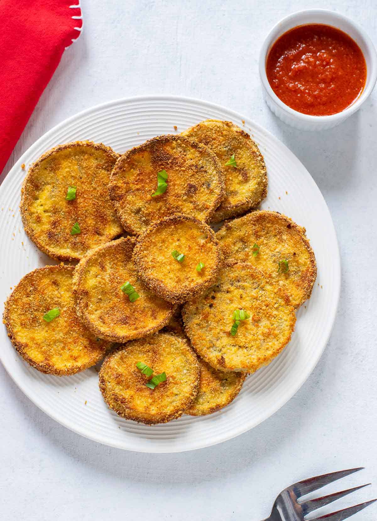 baked breaded eggplant slices on plate with marinara on side