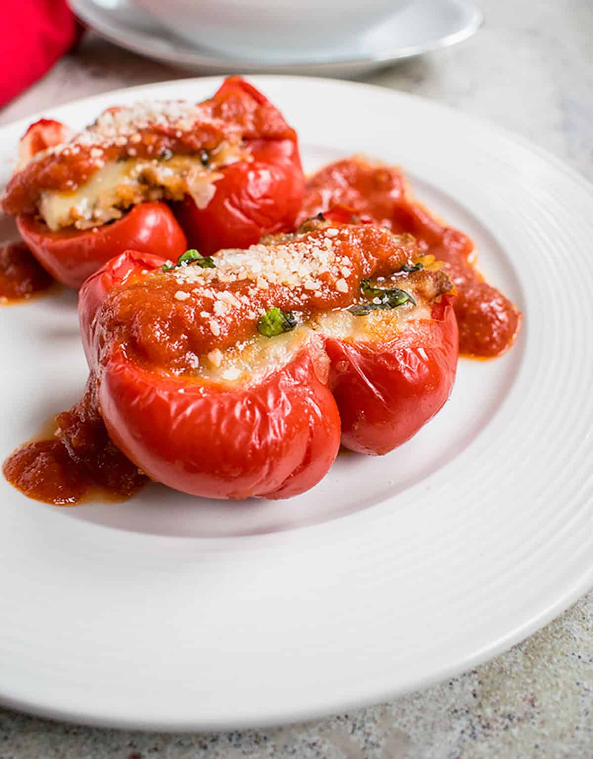 plate of Italian stuffed peppers with marinara and grated cheese