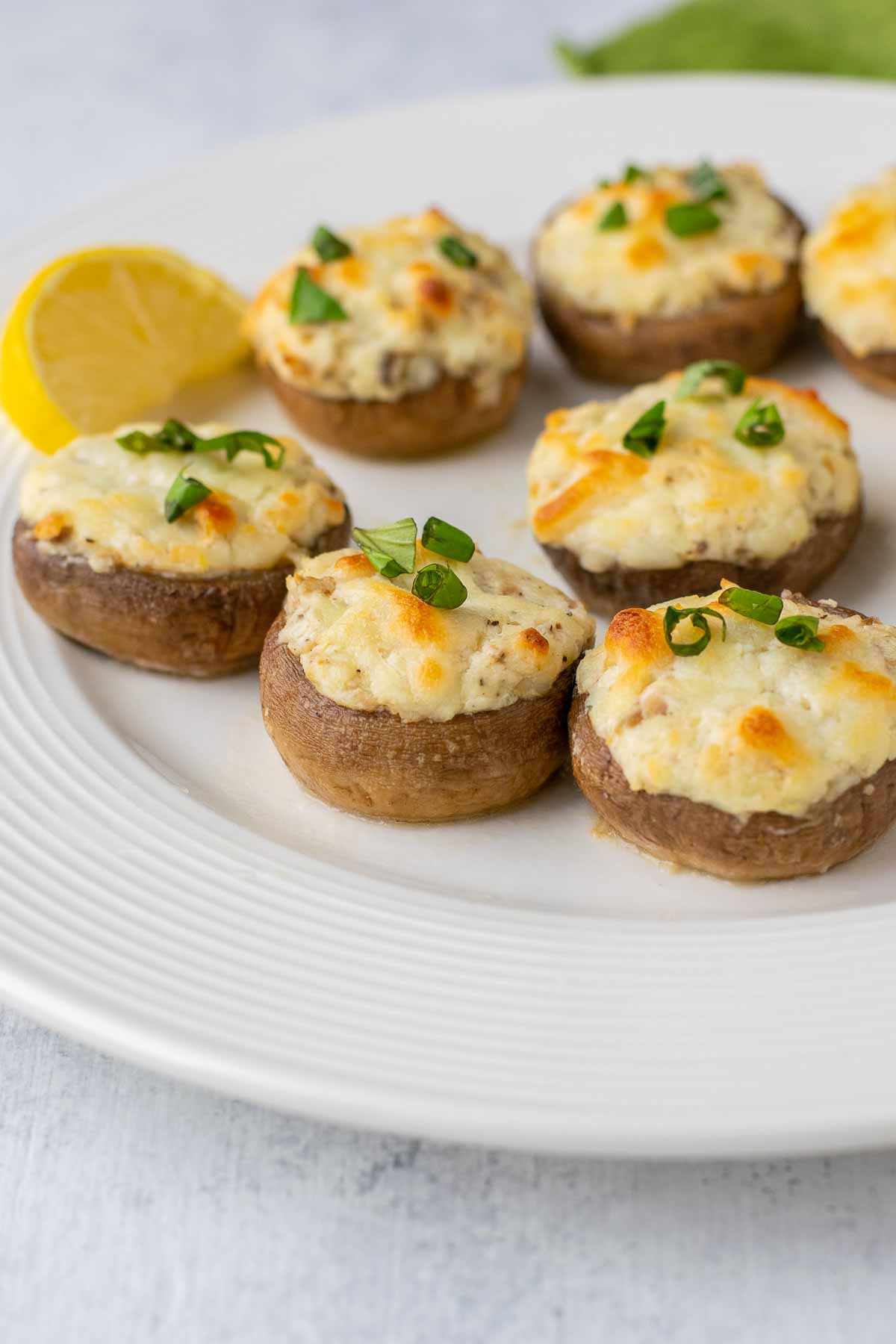 stuffed mushrooms with cream cheese on plate with lemon, basil.