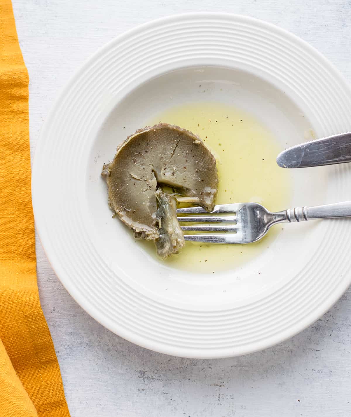 cooked artichoke heart in oil with a forkful of the heart