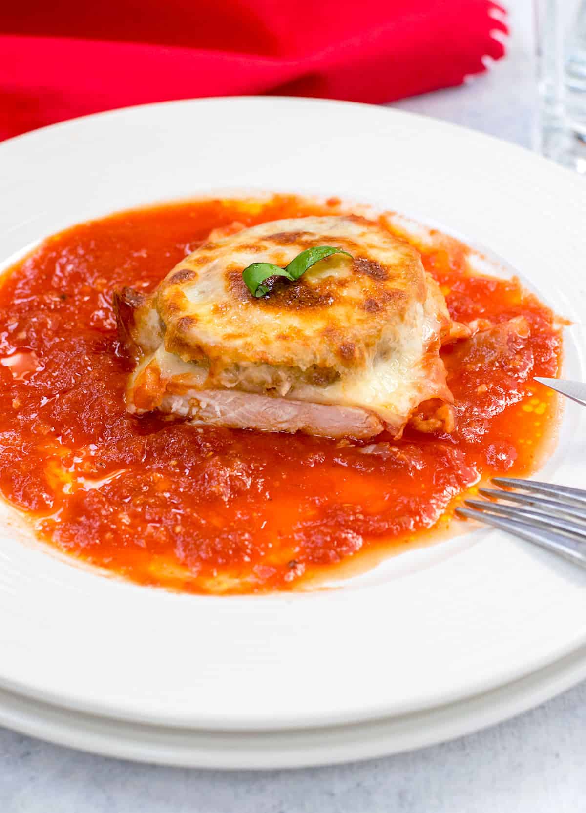 Chicken topped with melted cheese and eggplant in a pool of tomato sauce 
