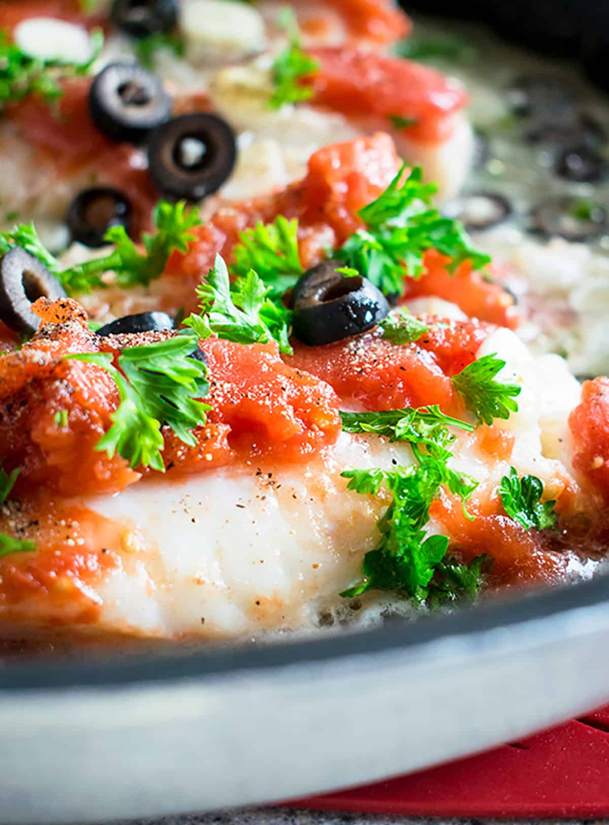 cod with tomatoes and olives in skillet