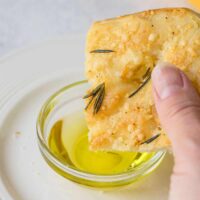 dipping Parmesan focaccia with rosemary into oil