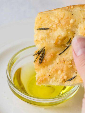 dipping Parmesan focaccia with rosemary into oil