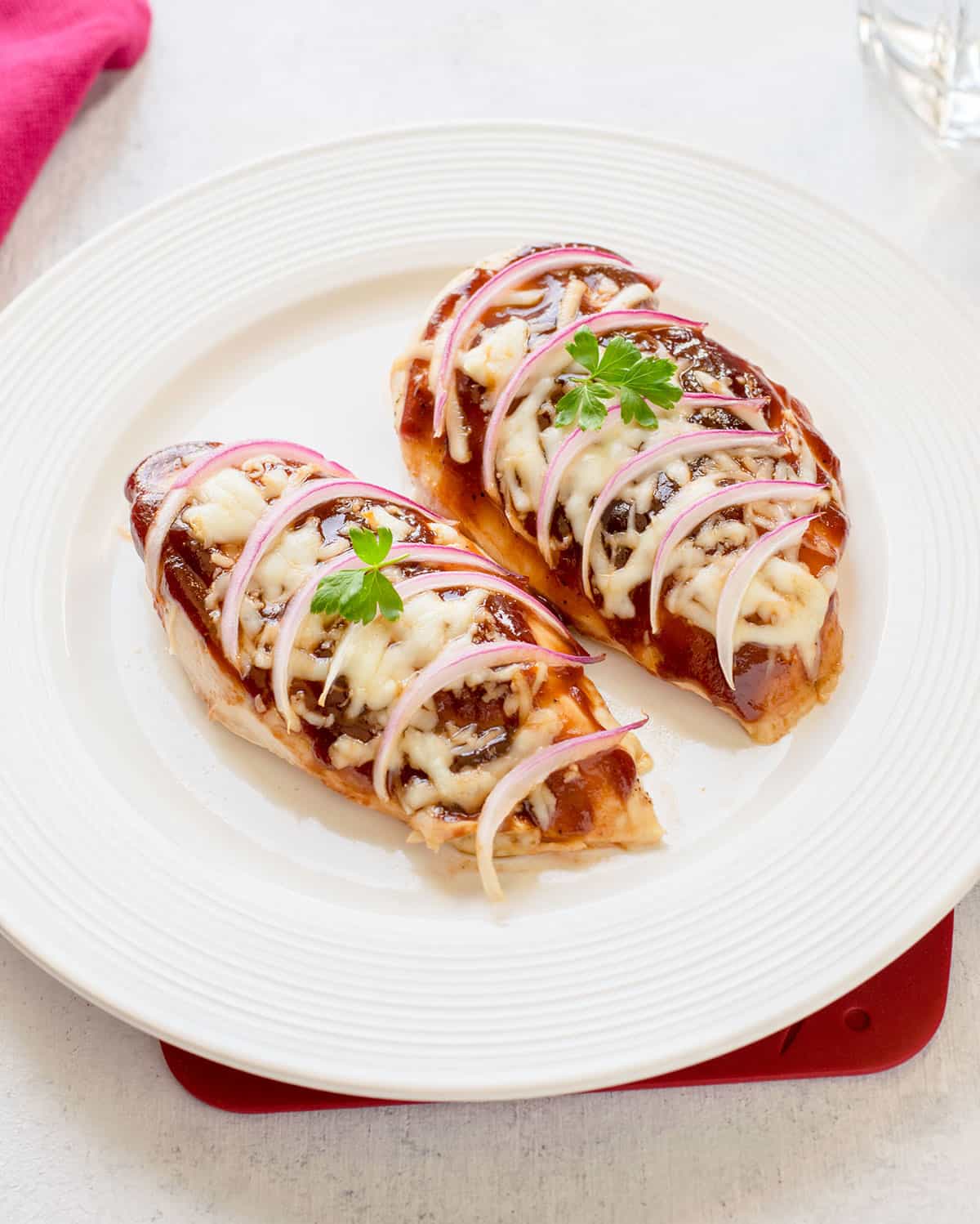 BBQ chicken breasts with mozzarella and onions on white plate