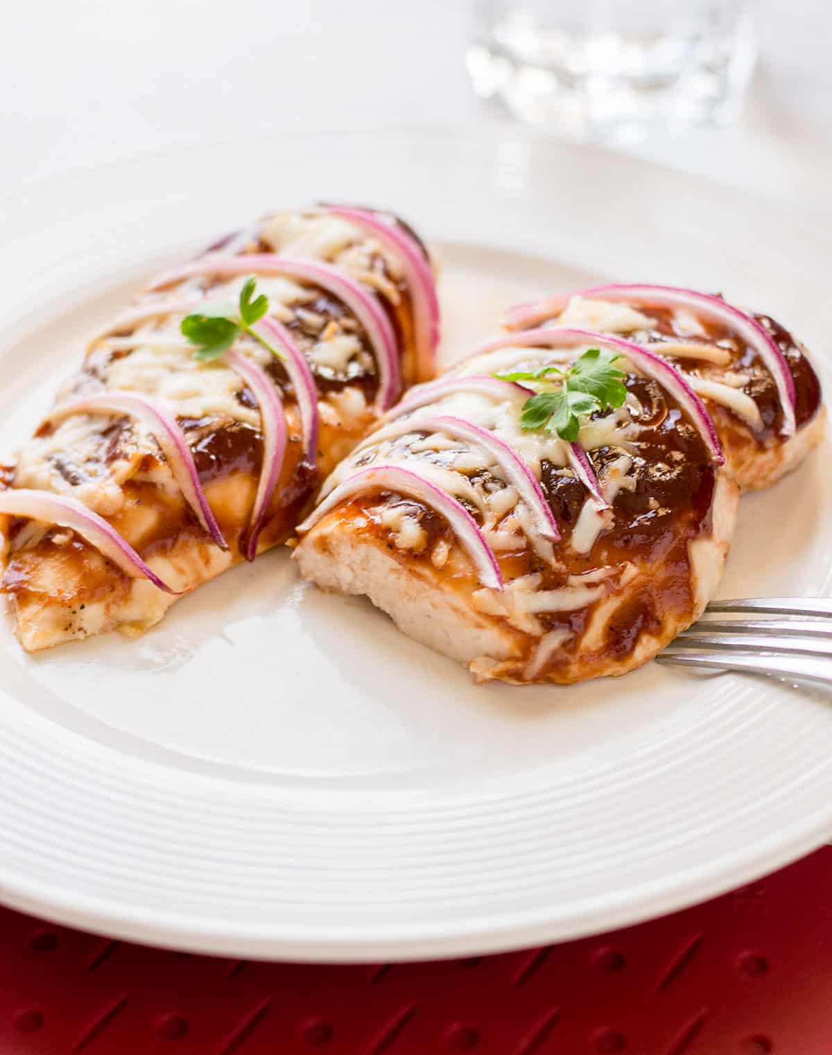 baked bbq chicken breasts with mozzarella and onions on plate
