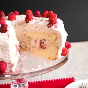 angel food cake with raspberries and cream on cake stand