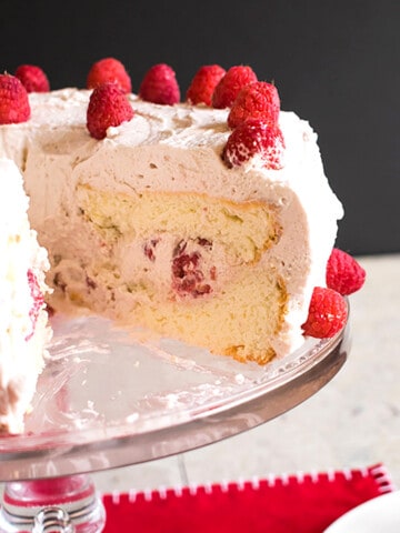 angel food cake with raspberries and cream on cake stand