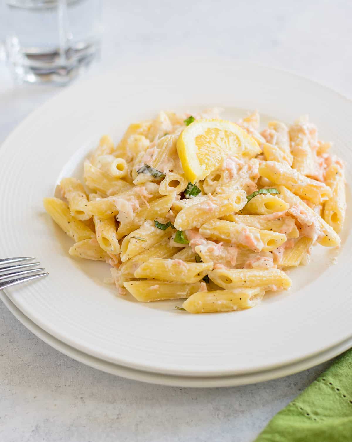 penne pasta with salmon, lemon and basil on plate with fork
