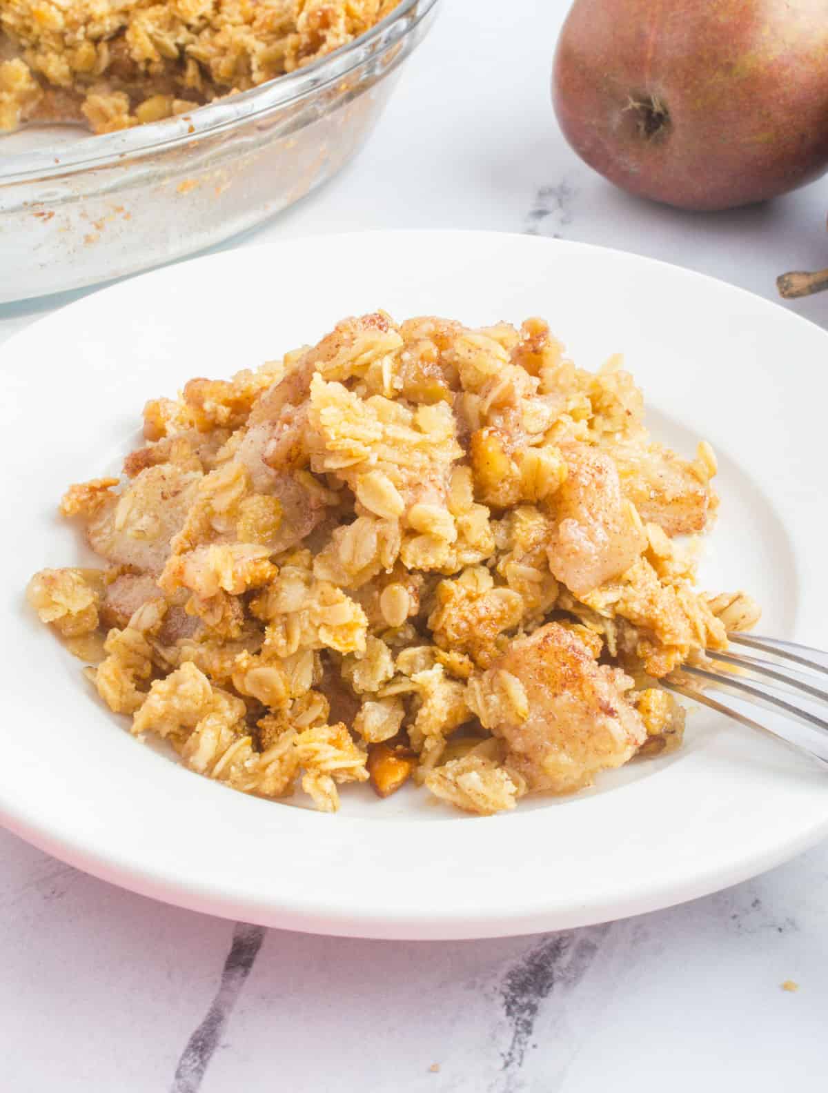 plate of pear crisp with oats and fork