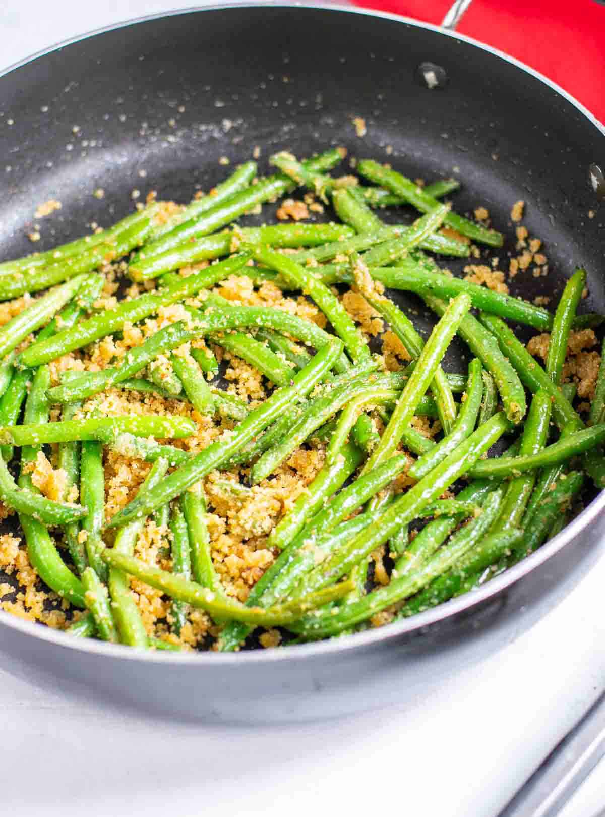 skillet of cooked green beans with bread crumbs