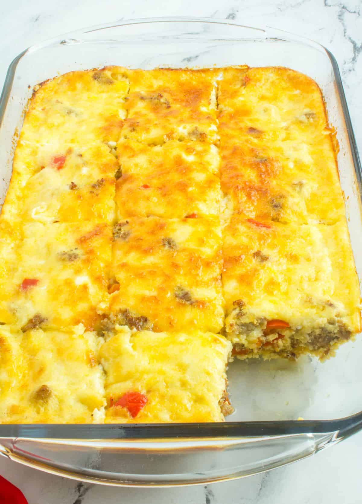 sausage and egg casserole in glass pan with slice missing