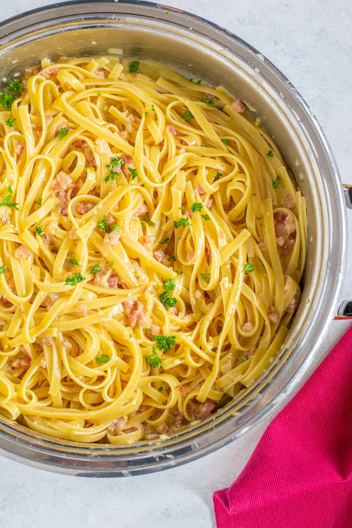 pan of fettuccine carbonara with pancetta and parsley