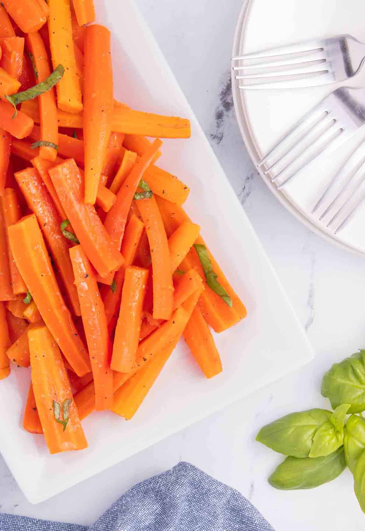 carrot salad on platter with basil leaves and forks