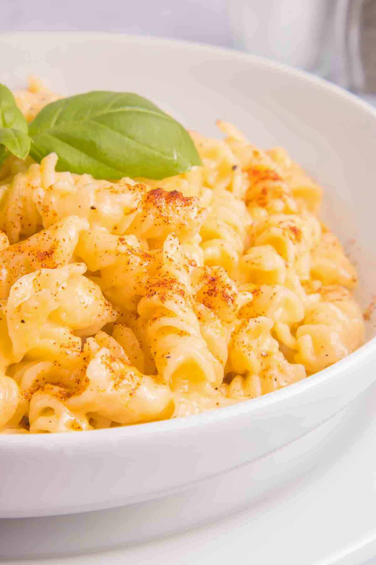 bowl of mac and cheese with basil leaves