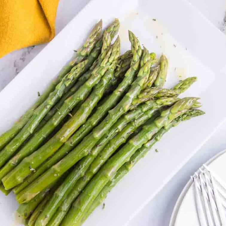 cooked asparagus with melted butter on platter