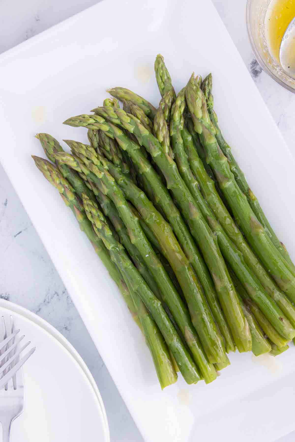 platter of cooked asparagus with melted butter