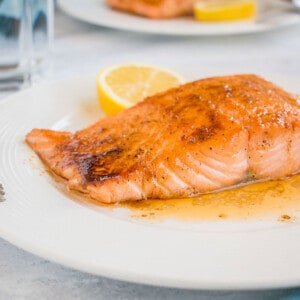 maple-glazed salmon on white plate with lemon