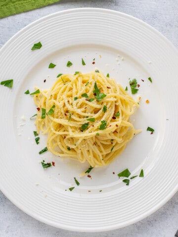 cooked spaghetti in a plate with parsley.