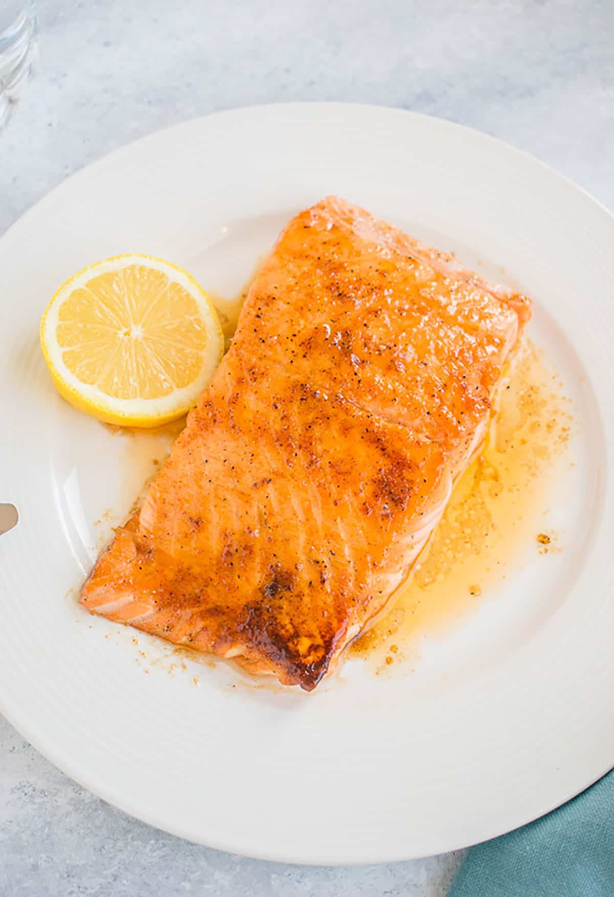 glazed salmon in a pool of butter on plate with lemon