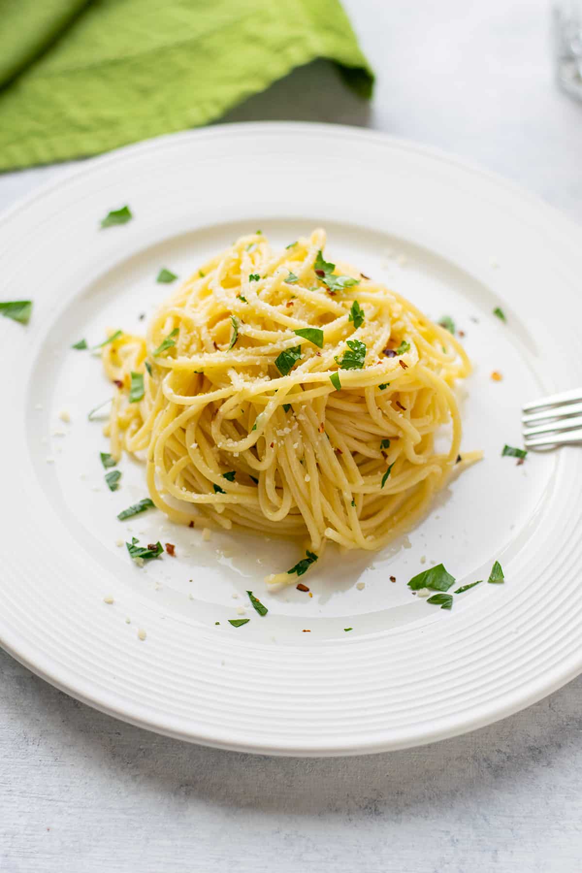cooked spaghetti in a dish with parsley and a fork